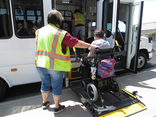Wheelchair Accessible Bus with driver assisting person in a wheelchair onto lift